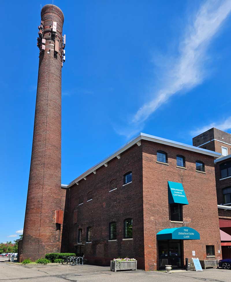 Historic brick Innovation Café building and tall mill smokestack at 128 Lakeside Avenue in Burlington, Vermont